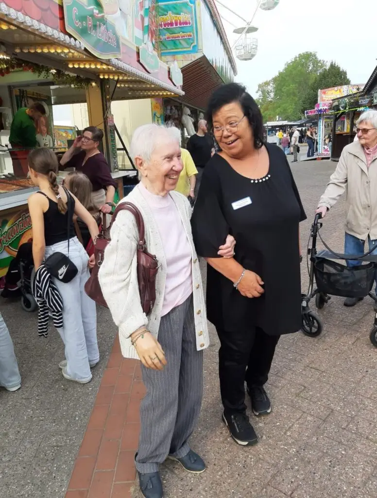 Bewohnerin und Betreuungskraft gehen gemeinsam über den Roonkarker Mart