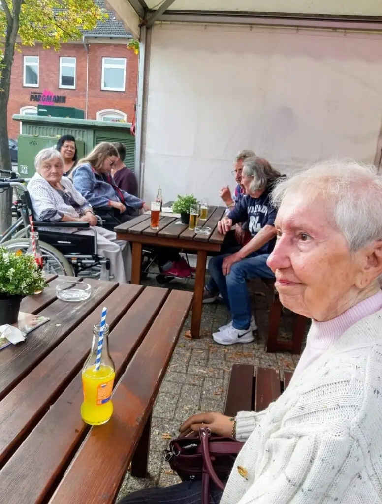 Bewohnerinnen und Bewohner sitzen an Tischen auf dem Roonkarker Mart