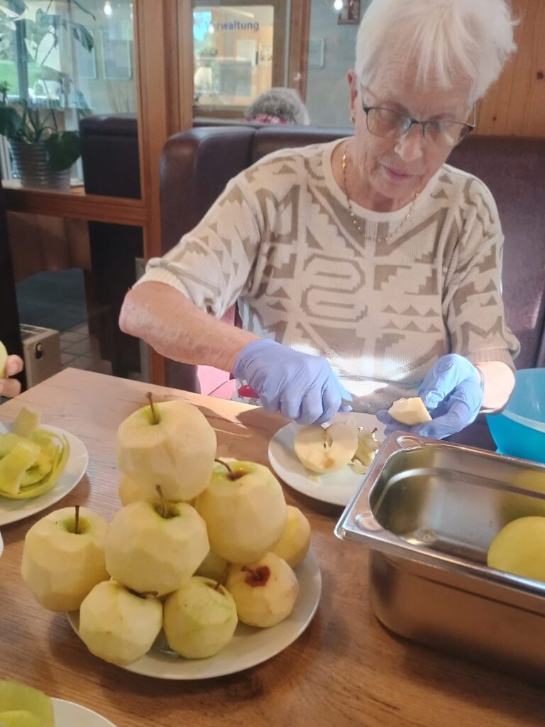 Eine Bewohnerin schneidet geschälte Äpfel für den Apfelkuchen
